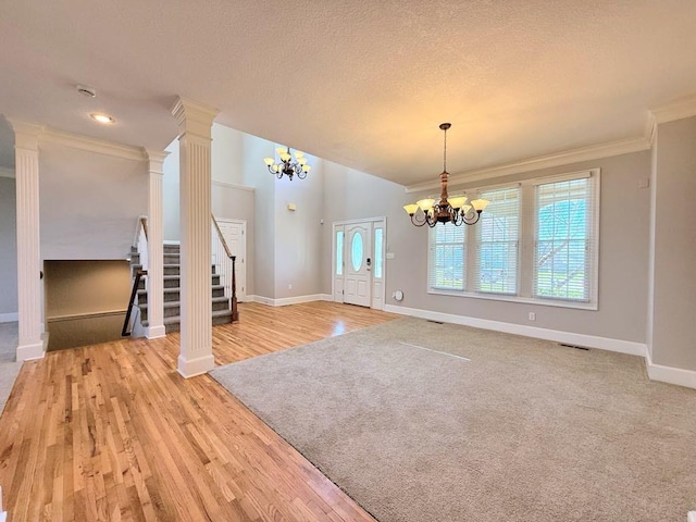 interior space featuring visible vents, a textured ceiling, baseboards, a chandelier, and ornate columns