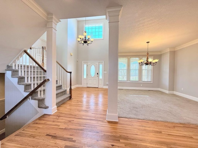 entrance foyer with stairs, decorative columns, and a chandelier