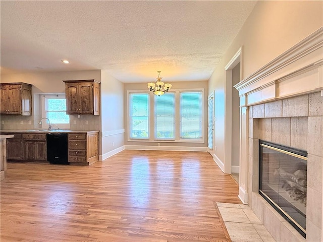 kitchen featuring an inviting chandelier, black dishwasher, light wood-style floors, and tasteful backsplash