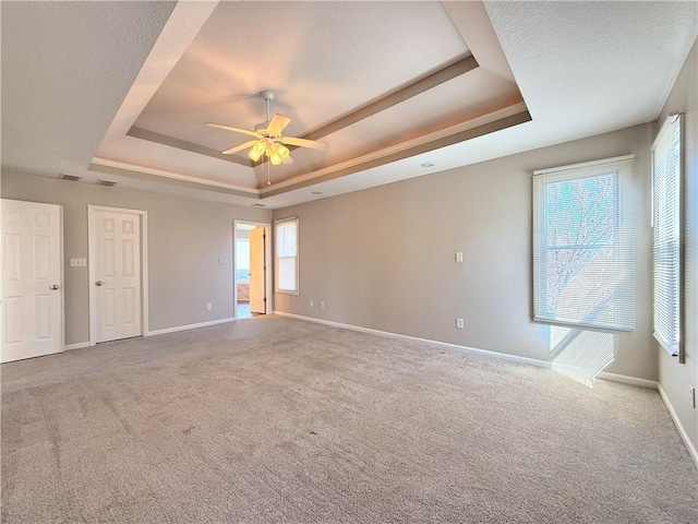 unfurnished room with baseboards, a raised ceiling, carpet floors, and a ceiling fan