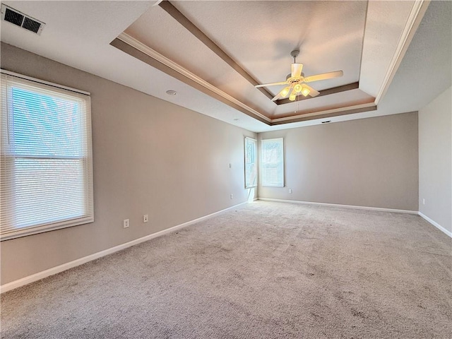 spare room featuring visible vents, carpet flooring, a raised ceiling, and baseboards