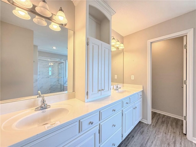 full bathroom with a sink, double vanity, wood finished floors, and a shower stall