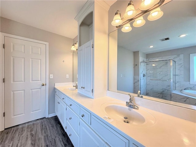 bathroom with double vanity, a shower stall, wood finished floors, and a sink
