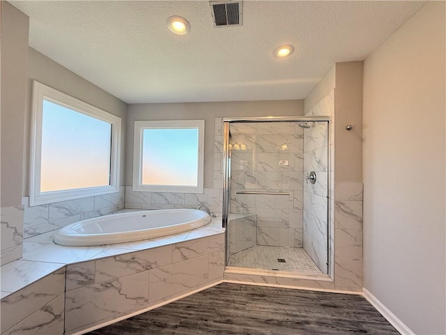 bathroom featuring visible vents, a shower stall, wood finished floors, a bath, and a textured ceiling