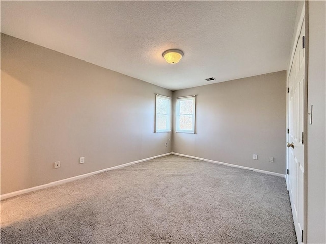 empty room featuring baseboards, visible vents, carpet floors, and a textured ceiling