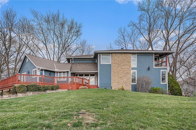 back of house with a wooden deck, a yard, and roof with shingles
