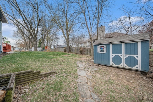 view of yard featuring an outdoor structure, a fenced backyard, a shed, and a playground