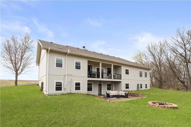rear view of house featuring a balcony, a lawn, an outdoor living space with a fire pit, a patio, and stucco siding