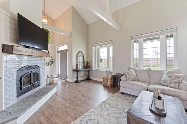 living room featuring baseboards, wood finished floors, a brick fireplace, and high vaulted ceiling