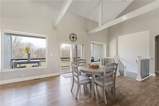 dining room featuring visible vents, baseboards, wood finished floors, and high vaulted ceiling