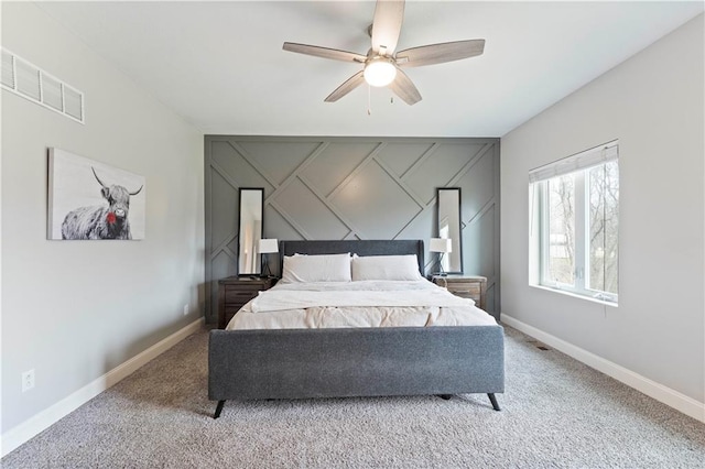 bedroom with visible vents, light carpet, a decorative wall, baseboards, and ceiling fan