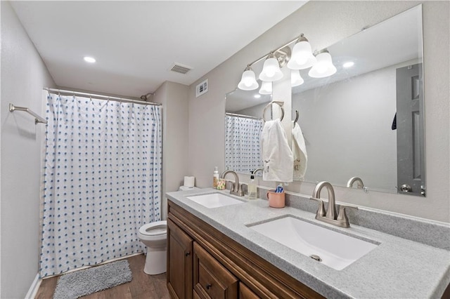 bathroom with wood finished floors, visible vents, toilet, and a sink