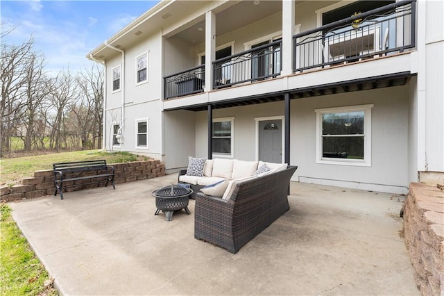 view of patio with a balcony and an outdoor living space with a fire pit