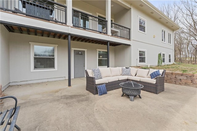 view of patio featuring an outdoor living space with a fire pit and a balcony