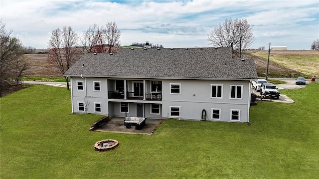 rear view of property with a yard, a patio area, roof with shingles, and an outdoor living space with a fire pit