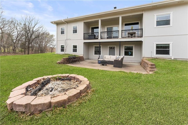 rear view of property with a patio area, a balcony, an outdoor living space with a fire pit, and a yard