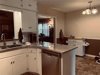 kitchen with white cabinetry, a sink, a peninsula, and dishwasher