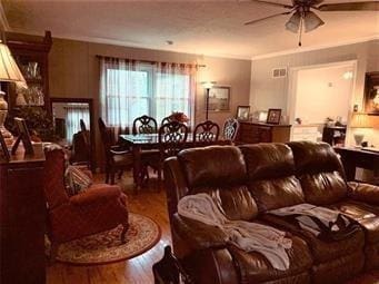 living area featuring wood finished floors, crown molding, and ceiling fan
