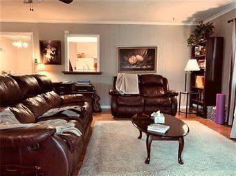 living area featuring ceiling fan, wood finished floors, and crown molding