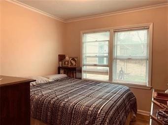 bedroom featuring ornamental molding, multiple windows, and wood finished floors