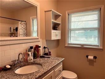 bathroom featuring a shower with curtain, toilet, vanity, and decorative backsplash