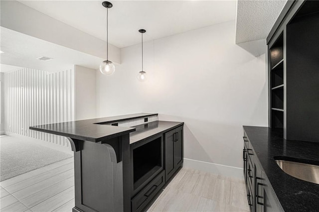 2317 SW Morris Dr, Lees Summit, MO 64082 - kitchen with dark cabinetry, hanging light fixtures, a breakfast bar area, and dark stone counters