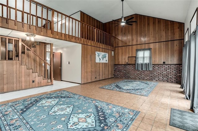 134 Timber Valley Dr, Linn Valley, KS 66040 - interior space featuring wooden walls, ceiling fan, tile patterned floors, high vaulted ceiling, and stairway