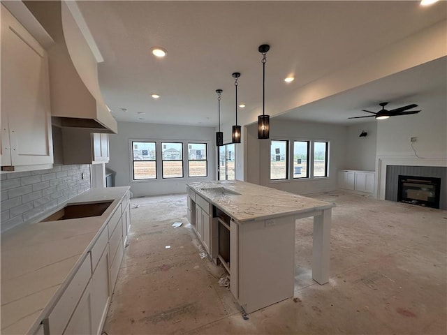 kitchen with a fireplace, tasteful backsplash, white cabinets, a kitchen island, and open floor plan