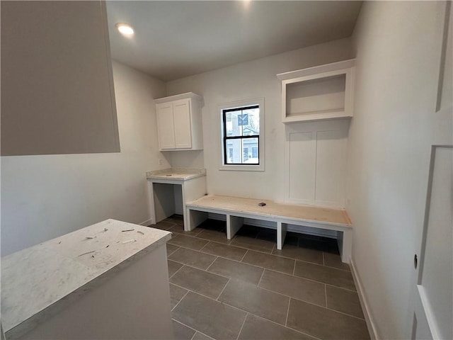 mudroom with dark tile patterned floors and baseboards