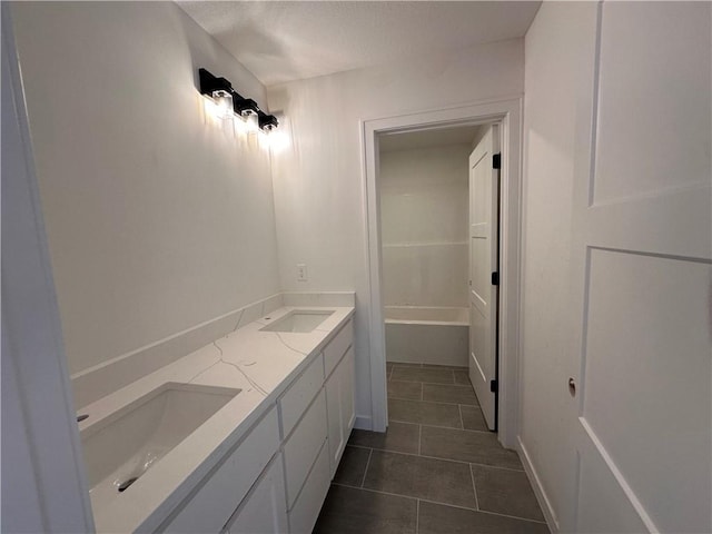 bathroom with a textured ceiling, double vanity, a sink, and tile patterned flooring