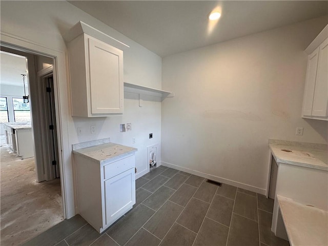 clothes washing area featuring visible vents, hookup for an electric dryer, baseboards, and cabinet space