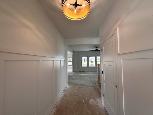 hallway featuring a decorative wall and a wainscoted wall