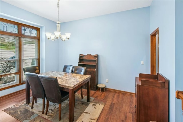 dining space featuring baseboards, an inviting chandelier, and wood finished floors