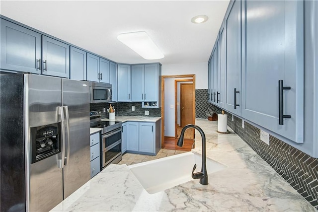 kitchen with a sink, decorative backsplash, light stone countertops, and stainless steel appliances