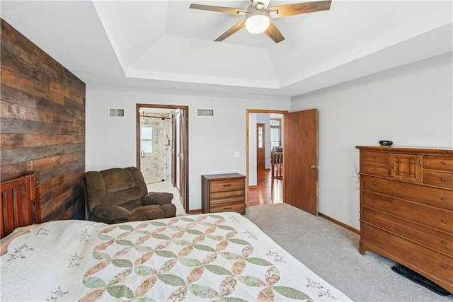 carpeted bedroom with ensuite bath, visible vents, a tray ceiling, and baseboards