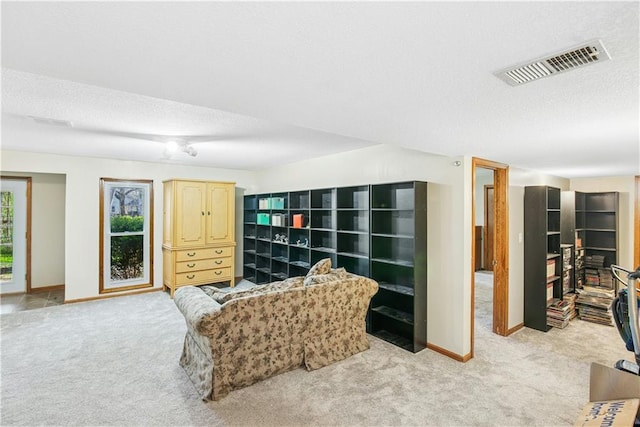 sitting room with visible vents, baseboards, light colored carpet, and a textured ceiling