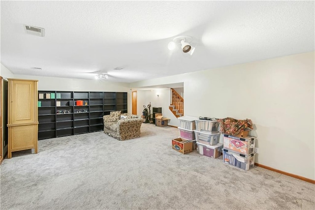 living area featuring a textured ceiling, stairs, visible vents, and carpet floors