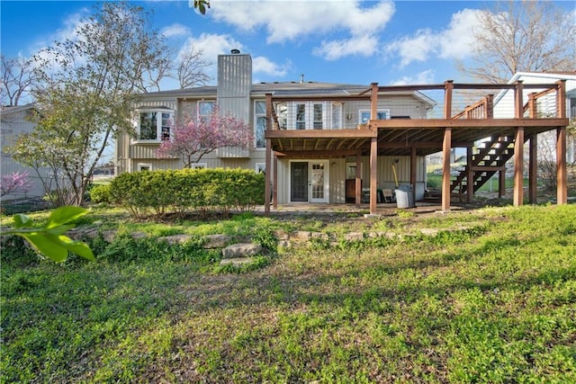 back of property with stairway, french doors, a wooden deck, and a chimney