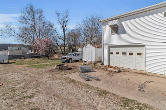 208 E 5th St, Carrollton, MO 64633 - view of yard with a storage unit, a fire pit, an outdoor structure, and fence