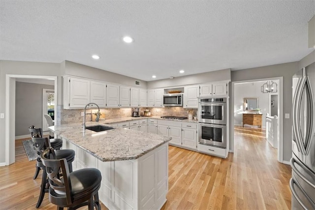 kitchen featuring a sink, white cabinets, a peninsula, and stainless steel appliances