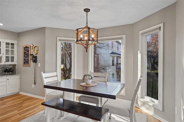 dining area with baseboards, a notable chandelier, a textured ceiling, light wood finished floors, and recessed lighting