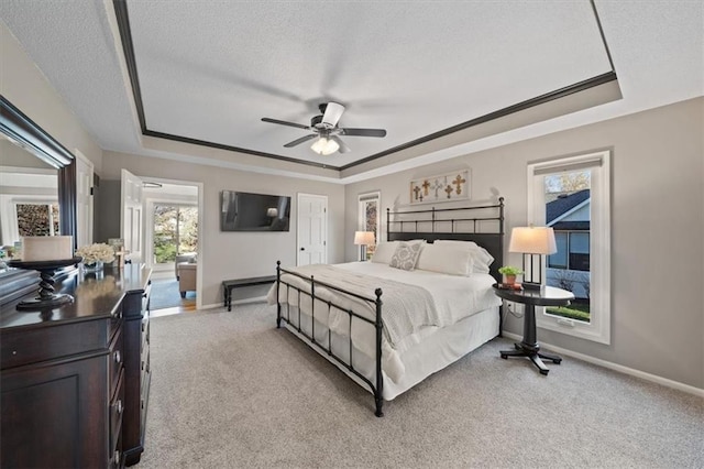 bedroom featuring light carpet, a tray ceiling, and baseboards