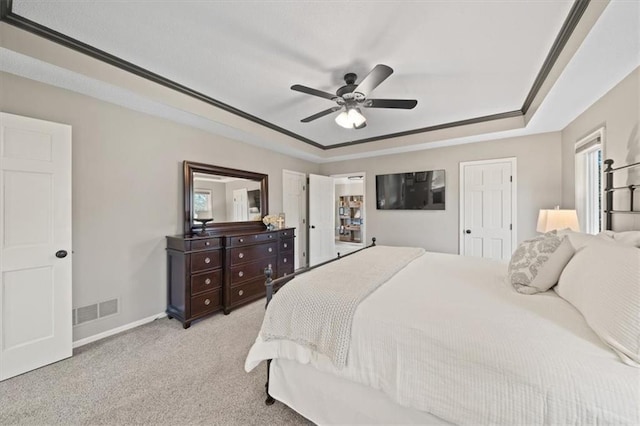 bedroom with a ceiling fan, visible vents, light carpet, a raised ceiling, and baseboards
