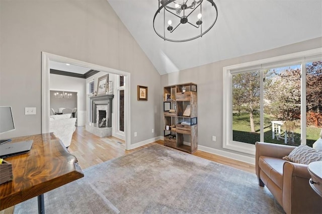 interior space with baseboards, a chandelier, a fireplace with raised hearth, high vaulted ceiling, and wood finished floors