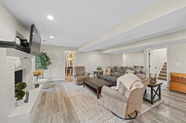 living area featuring baseboards, recessed lighting, a fireplace, stairway, and light wood-style flooring