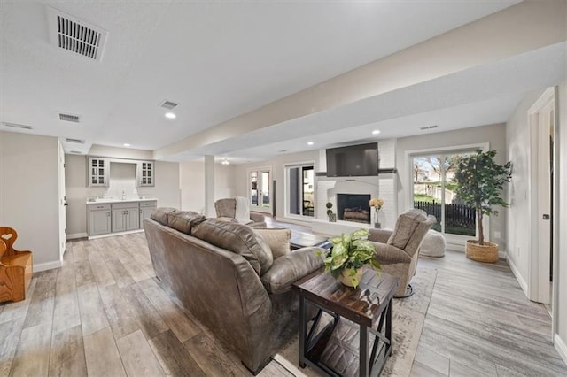 living area featuring light wood-style floors, baseboards, and visible vents