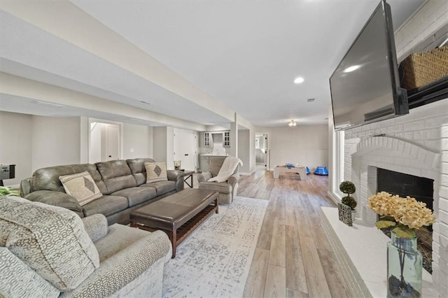 living room with recessed lighting, light wood finished floors, a brick fireplace, and baseboards
