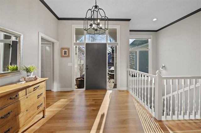 foyer entrance featuring crown molding, baseboards, an inviting chandelier, and light wood-style floors