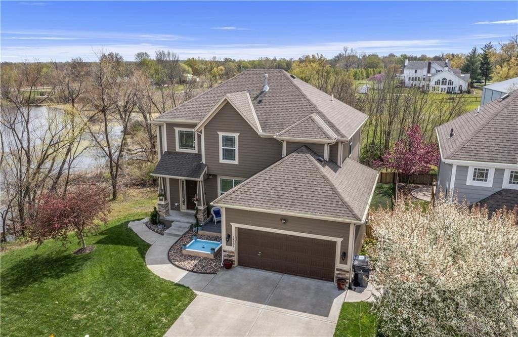 18505 W 165th St, Olathe, KS 66062 - view of front of house with a garage, concrete driveway, a front lawn, and a shingled roof