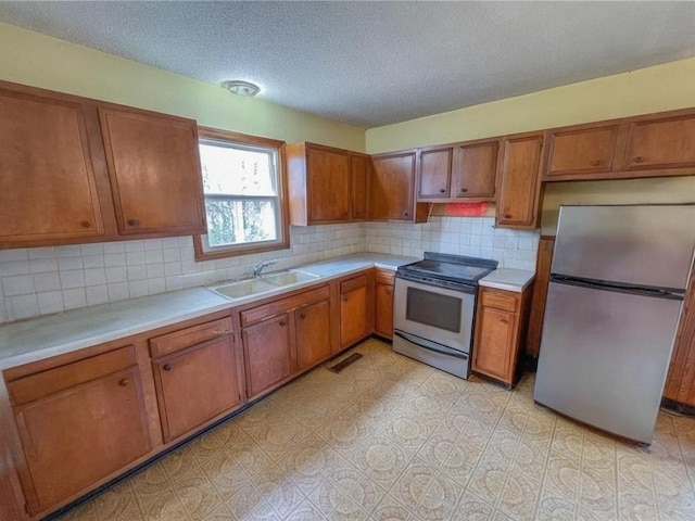kitchen with a sink, appliances with stainless steel finishes, brown cabinets, and light countertops